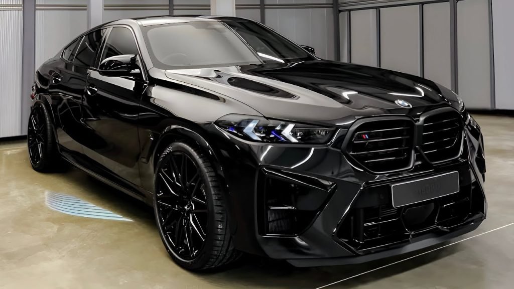 A sleek black BMW SUV with tinted windows and shiny black wheels, recently serviced for Chandler windshield replacement, is parked indoors on a polished concrete floor, surrounded by metallic-paneled walls.